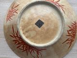 a brown plate with a red design on it on a table