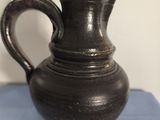 un vase noir posé sur un tissu bleu, sur une table