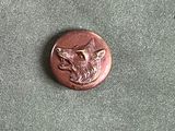 une image représentant un bouton en bronze orné d'une tête de loup