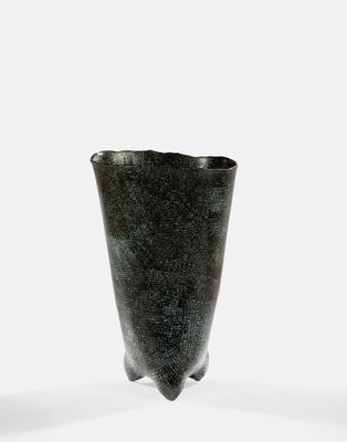 un vase noir posé sur une surface blanche
