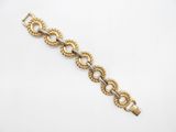 gros plan d'un bracelet en or sur une surface blanche