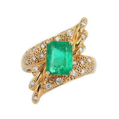 gros plan d'une bague en émeraude et diamant sur fond blanc