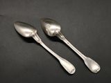 two silver spoons sitting on top of a table next to each other