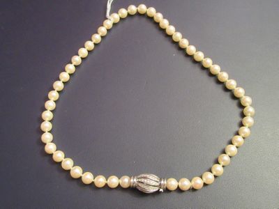 a close up of a necklace with pearls on a table