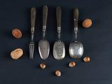 four spoons and two forks with nuts on a black surface