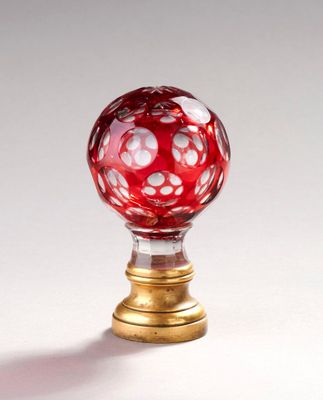 une boule de verre rouge posée sur un socle doré