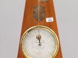 a wooden clock with a brass barometer on it
