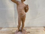 statue représentant un garçon en train de boire de l'eau à la bouteille, posée sur une table en bois