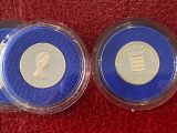two silver and blue coins sitting on top of a red cloth