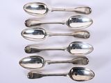six silver spoons sitting on top of each other on a white surface
