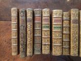 several old books are lined up in a row on a table