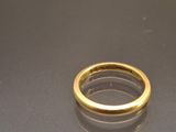 an image of a gold wedding ring on a black surface