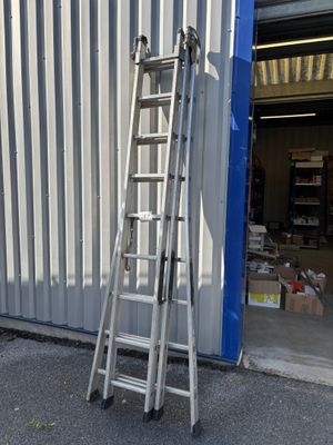 une échelle appuyée contre un immeuble, à côté d'une porte bleue