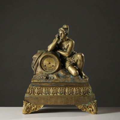 une statue en bronze représentant un homme assis au sommet d'une horloge