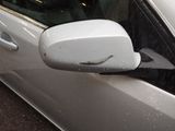 a side view mirror of a white car with snow on it