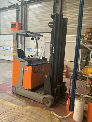 a forklift in a warehouse with a lot of pallets