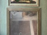 une photo d'un tableau accroché au mur au-dessus d'un miroir