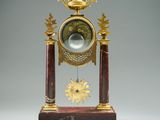 a clock that is sitting on a stand with a crown on top