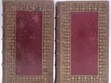 pair of antique leather bound books with red covers on white background