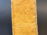 an old book sitting on top of a table next to a cell phone