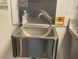 a stainless steel sink in a public restroom with a bottle of water