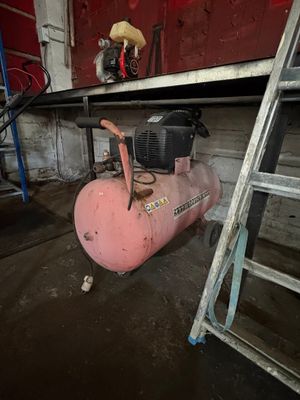a pink air compressor sitting next to a ladder