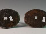 pair of bronze buttons with holes on them on a white surface