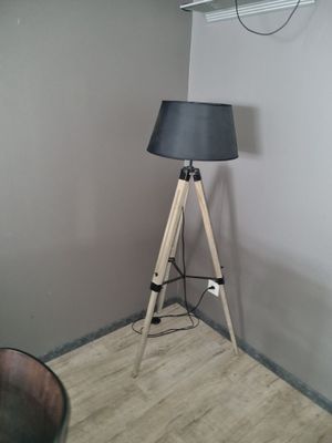une lampe posée sur un trépied en bois dans une pièce