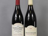 two bottles of red wine sit on a table next to each other