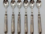 six silver spoons and a spoon on a white surface