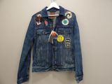 denim jacket with patches on it hanging on a hanger
