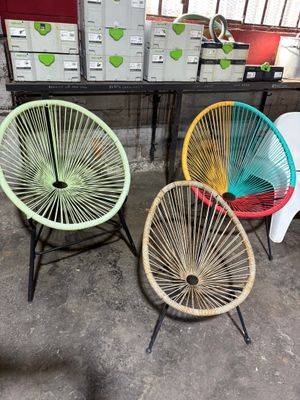 three colorful chairs sitting in a room with boxes of boxes in the background