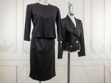 a black dress and jacket on a mannequin stand