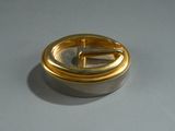 a small silver and gold object on a gray surface