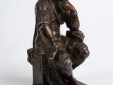 bronze statue of a man sitting on a bench with his hand on his chin