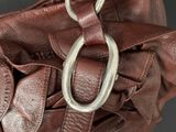 a brown leather purse with a metal hook on it