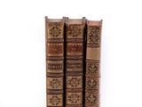three old books sitting on top of each other on a white surface