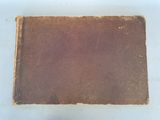 un vieux livre marron posé sur une table blanche