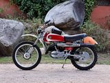 a red dirt bike parked in front of a large rock