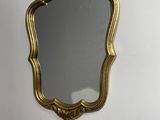 a gold mirror hanging on the wall above a sink