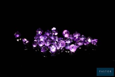 a close up of a bunch of purple crystals on a black surface