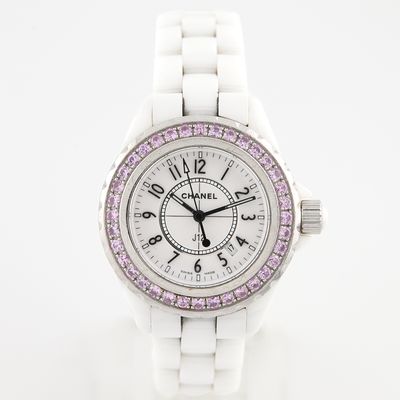 La montre est blanche et son cadran est orné de cristaux roses.