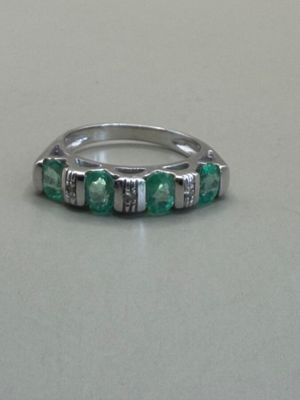 a silver ring with green stones on a table