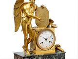 a statue of an angel holding a clock on a marble table
