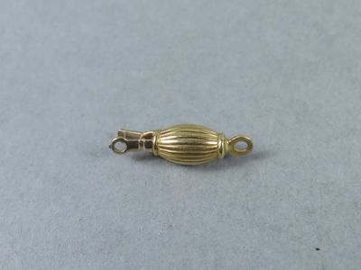 a close up of a gold plated bead on a white surface