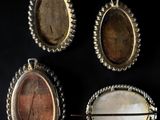 three silver and mother of pearl brooches on a black background