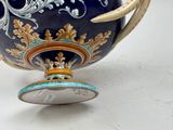 a blue and gold vase with a handle on a table