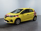 La petite voiture jaune est garée dans une grande pièce.