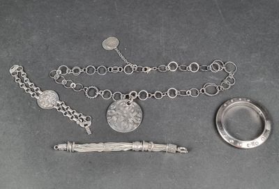 un collier, un bracelet et une bague en argent posés sur une table