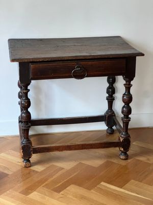 une petite table munie d'un tiroir, posée sur un parquet en bois massif
